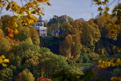 A sepia-toned photograph of the Fallsvale Historic Schoolhouse surrounded by autumn trees.