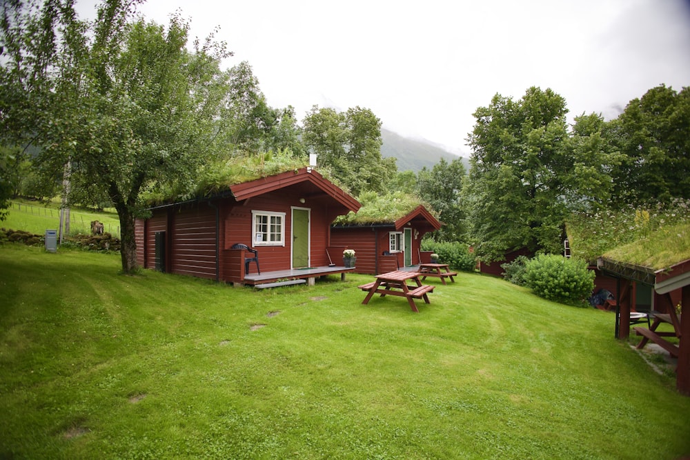 a small cabin with a grass roof and picnic tables