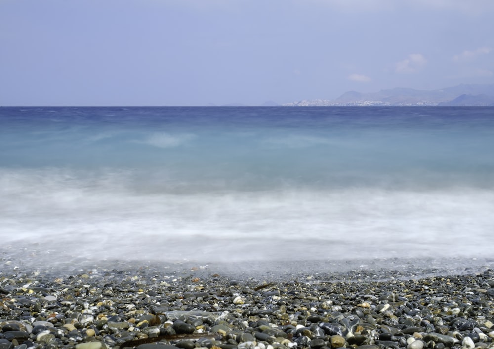 a rocky beach with a body of water in the background