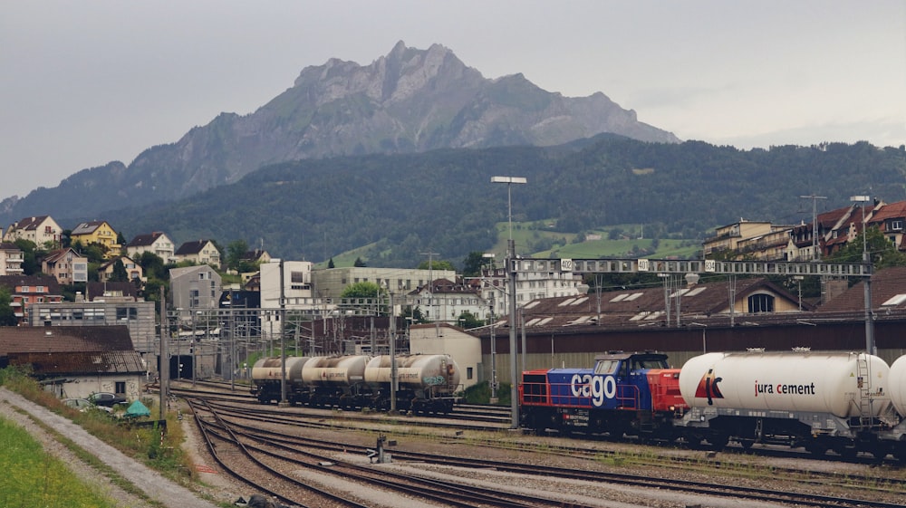 a train traveling down train tracks next to a lush green hillside