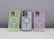 Three phone cases are displayed on a neutral background. The left case has a neon green border, the middle case contains a phone and has a gray border, while the right case features a pink border. Each case has a circular design in the center.