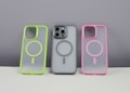 Three phone cases are displayed on a neutral background. The left case has a neon green border, the middle case contains a phone and has a gray border, while the right case features a pink border. Each case has a circular design in the center.