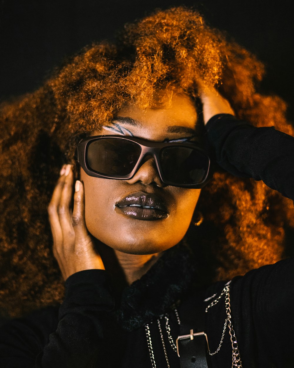 a woman with red curly hair wearing sunglasses