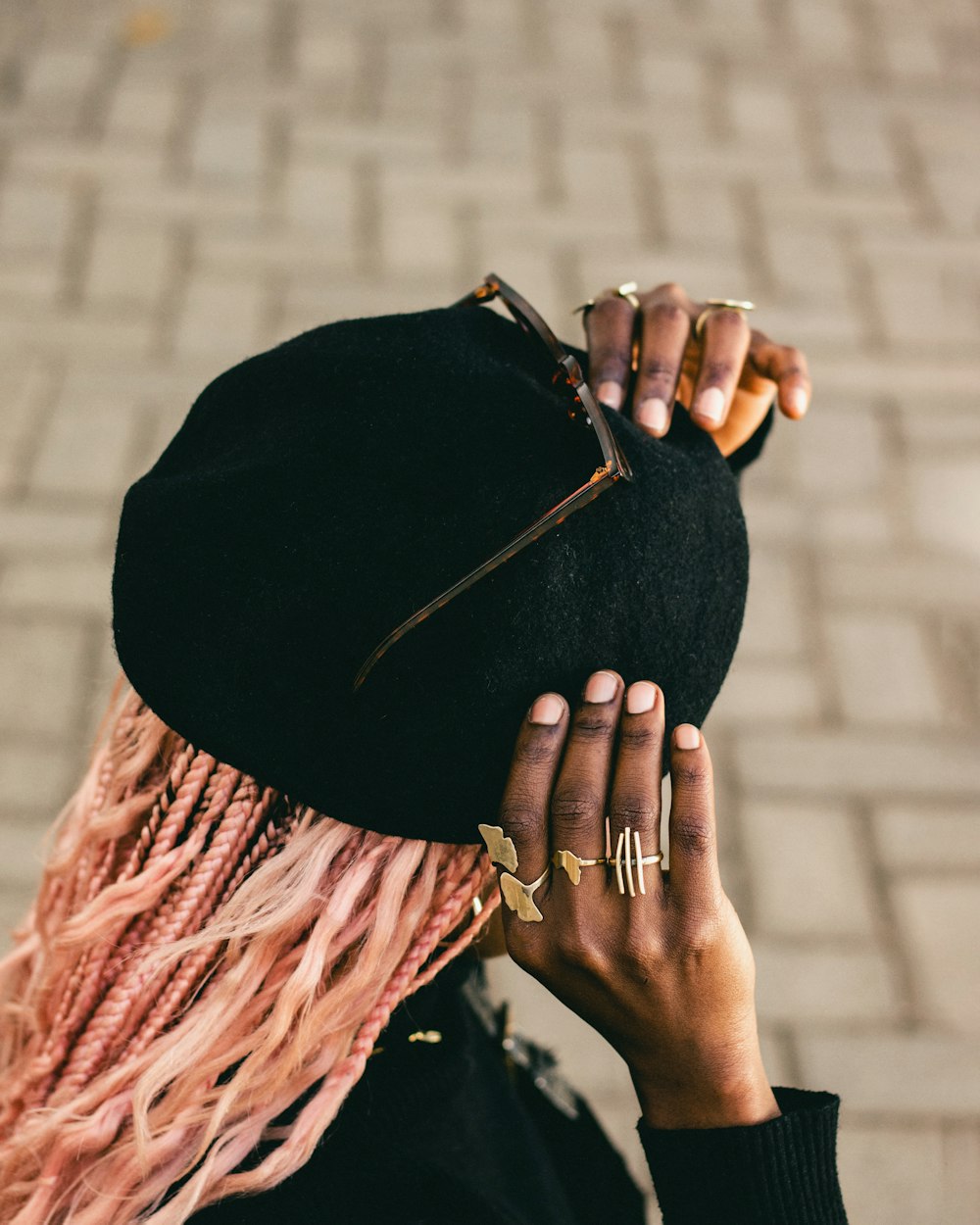 a woman with pink hair wearing a black hat