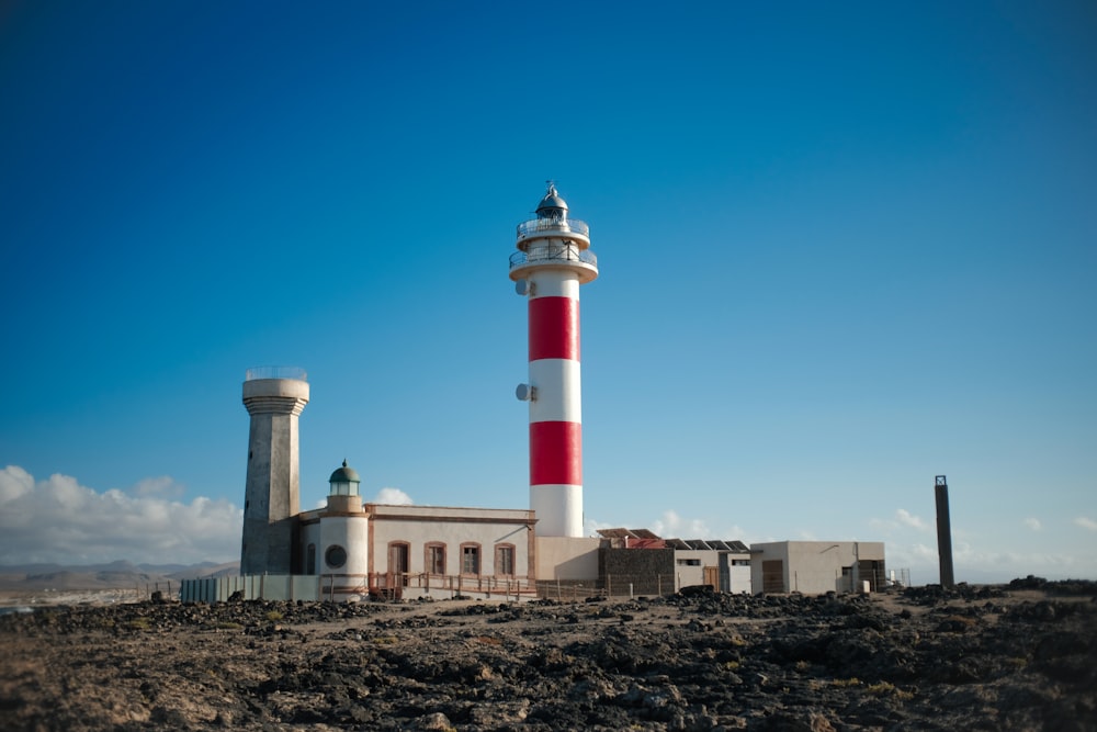 a red and white lighthouse sitting on top of a rocky beach