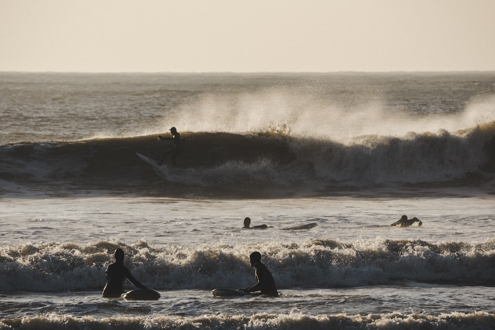 a group of people riding surfboards on top of a wave