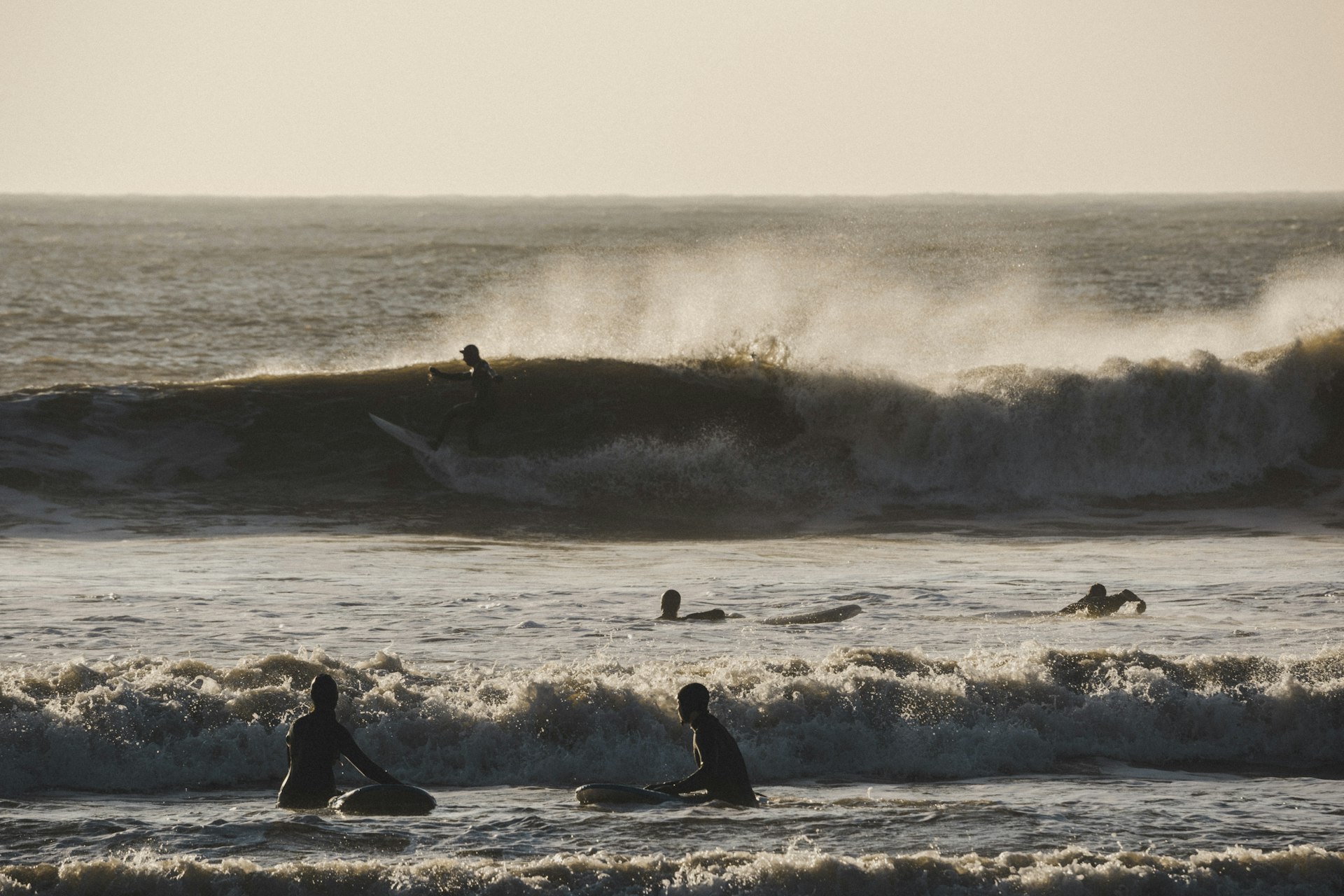 Group of surfers riding a wave at sunset