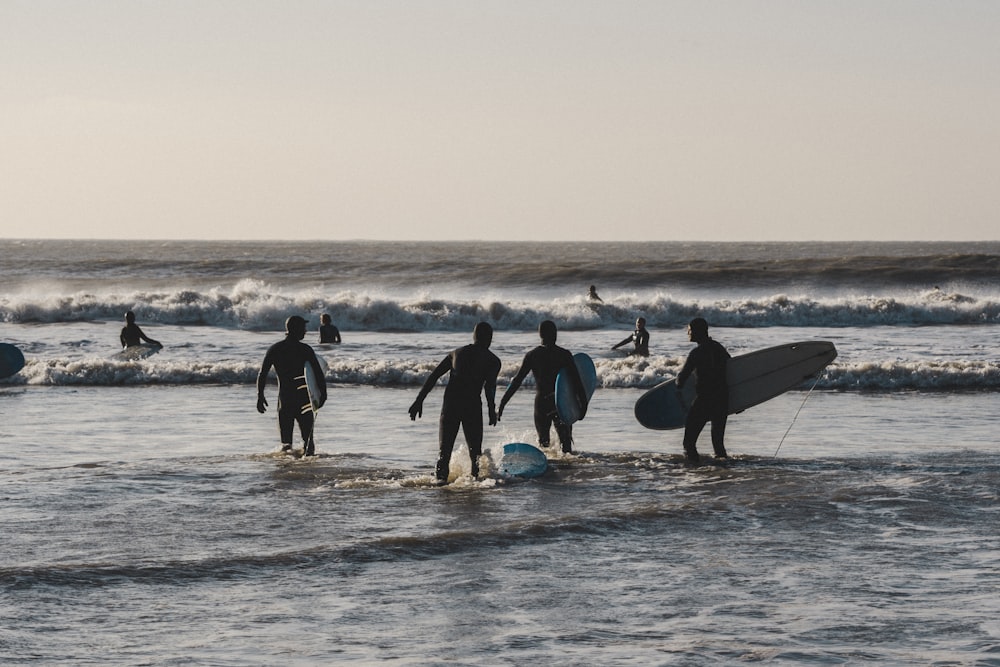a group of surfers walking into the ocean with their boards