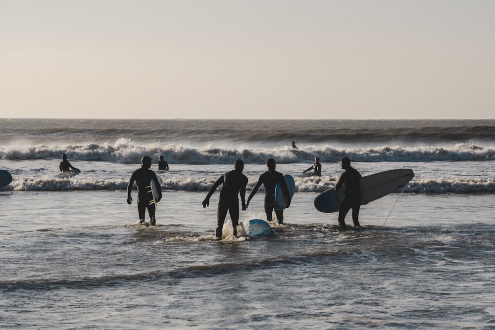 Un grupo de surfistas caminando hacia el océano con sus tablas