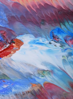 A vibrant abstract painting blending white, purple, green, orange, and blue hues.