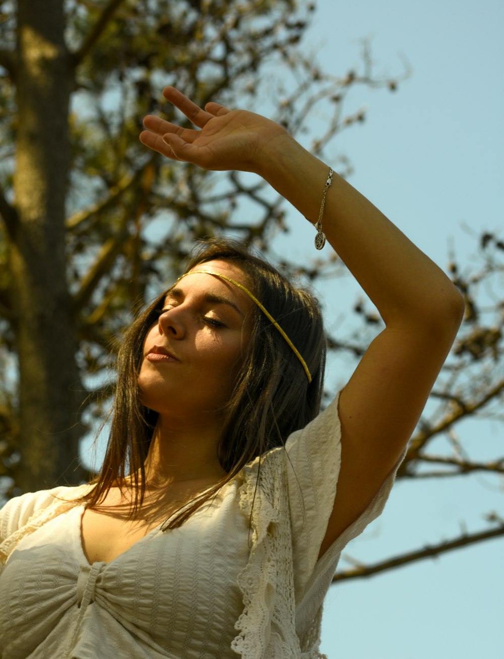 a woman standing in front of a tree holding her hand up