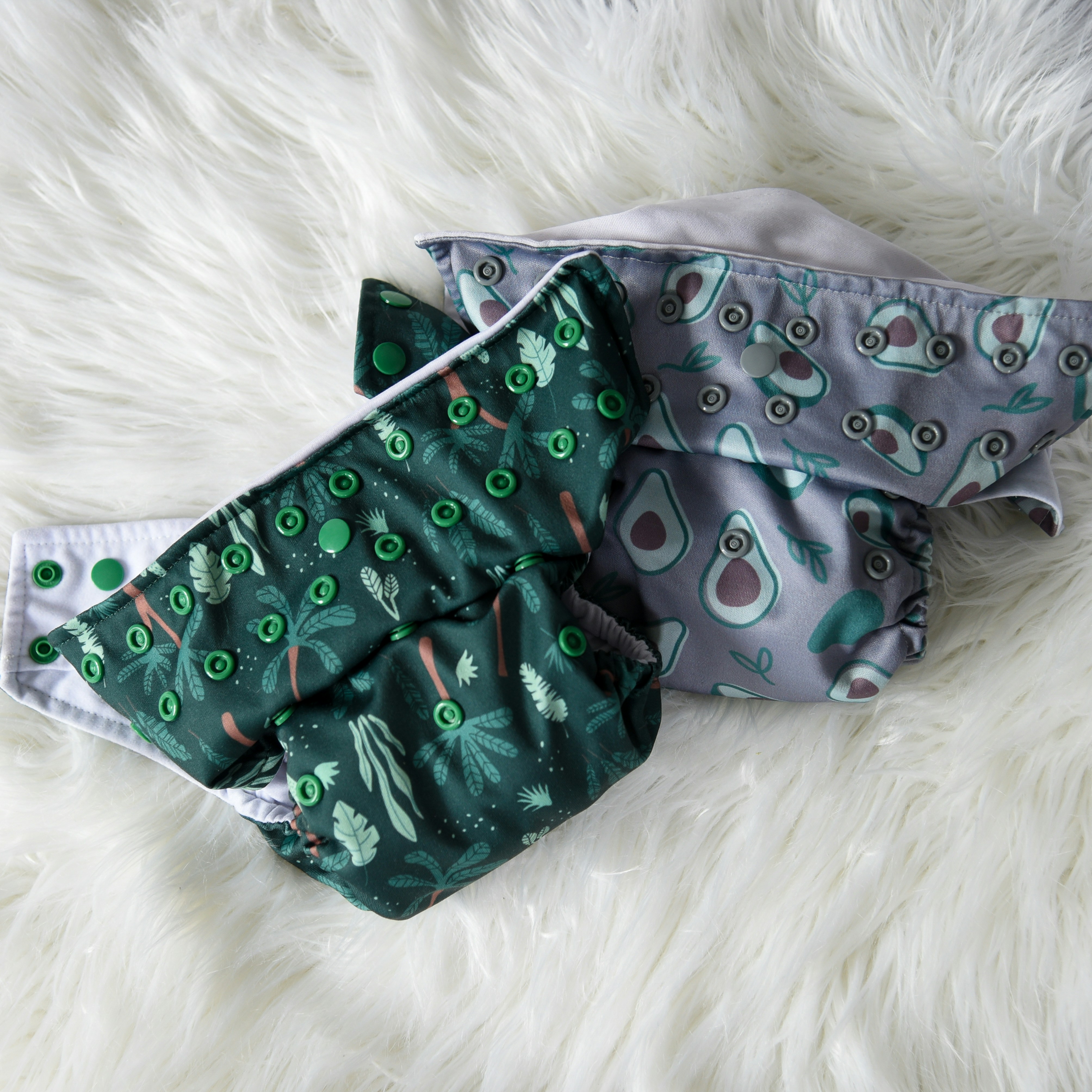 two cloth diapers laying on a white blanket