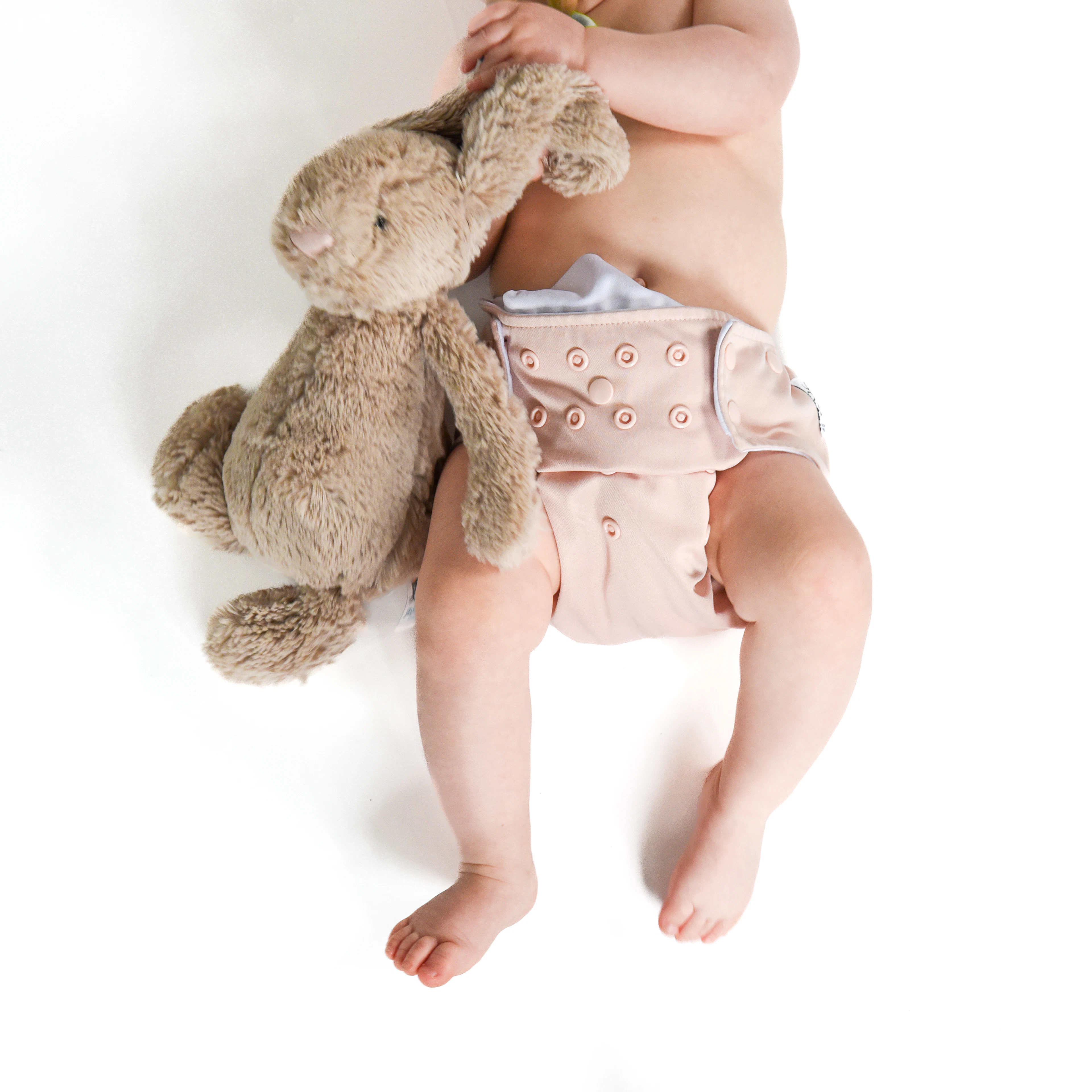 A baby in a nappy holding a teddy bear