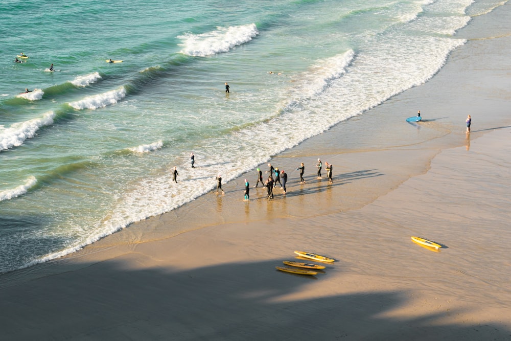 a group of people standing on top of a beach next to the ocean