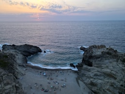 a group of people standing on top of a beach next to the ocean