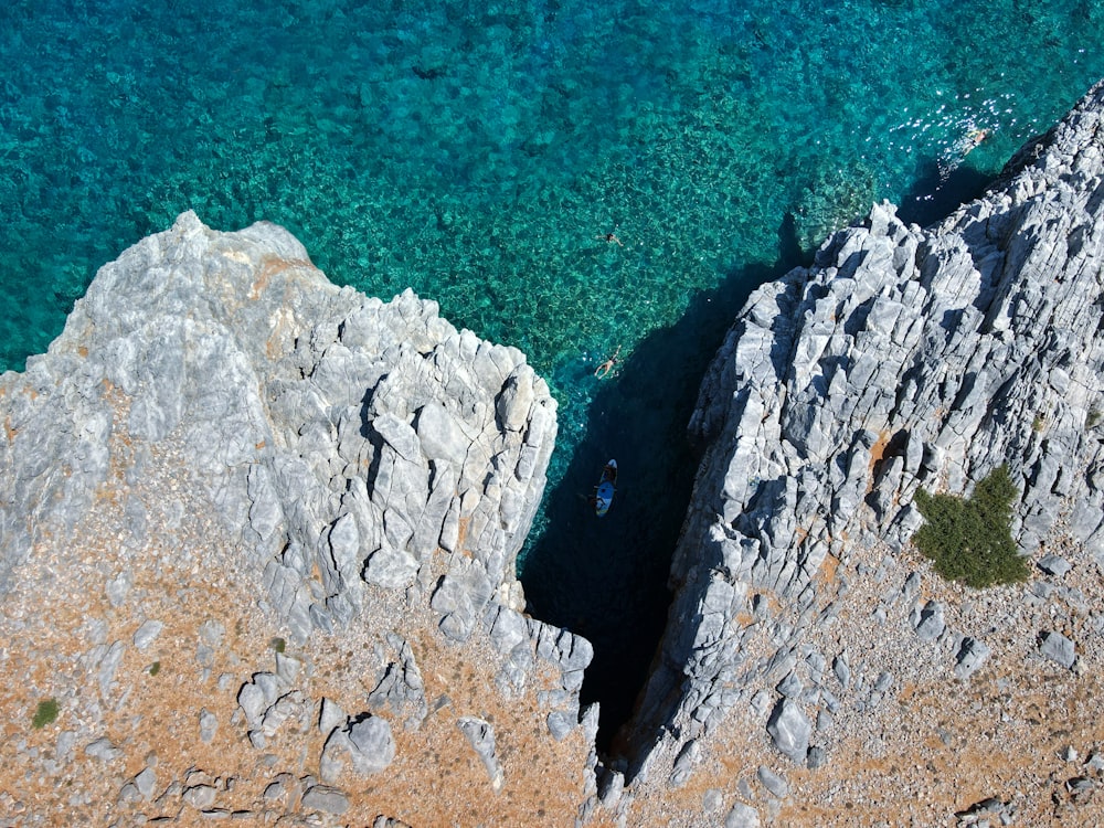 an aerial view of a rocky beach with clear blue water