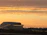 A sleek, modern portable office cabin set against a Qatar construction site at sunset.