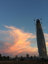 Modern building under construction with cranes and scaffolding at sunset.