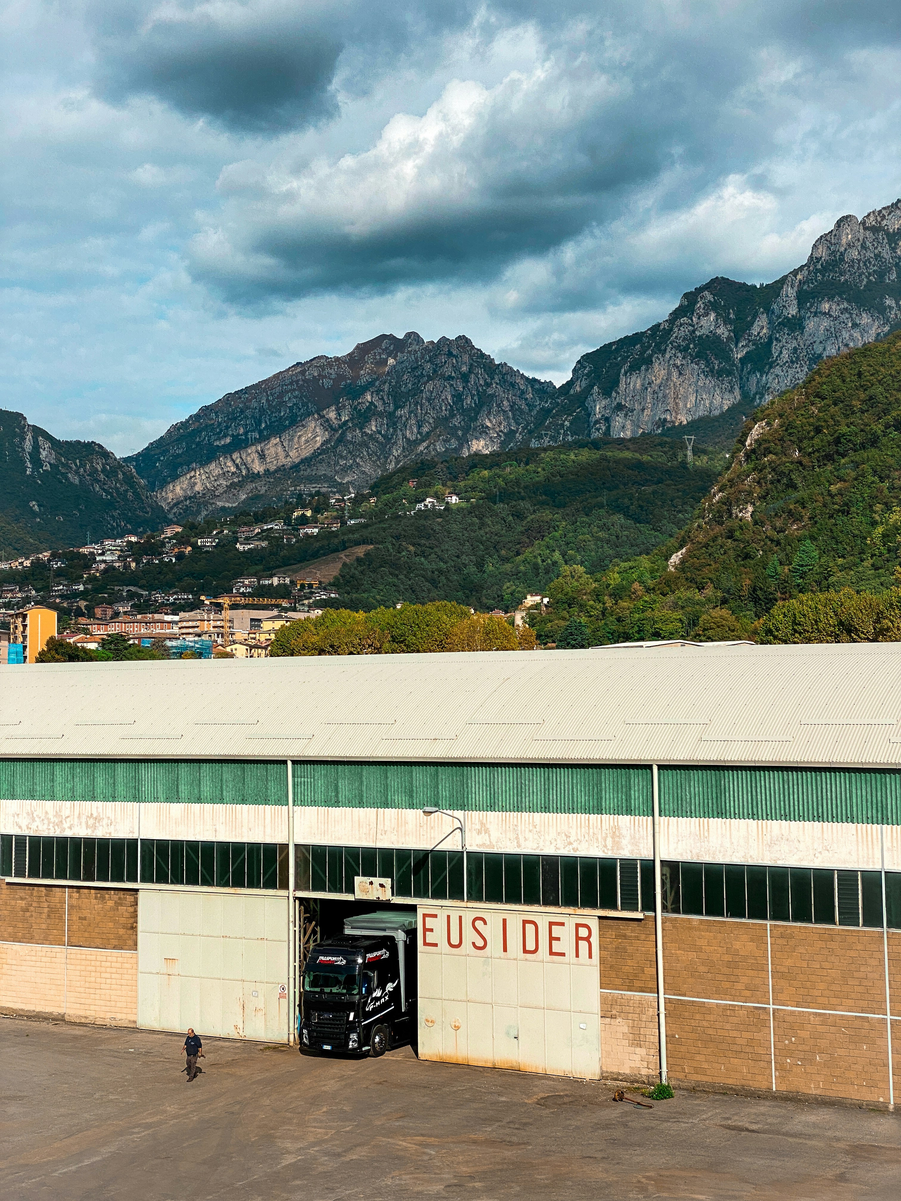 a truck parked in front of a building with mountains in the background