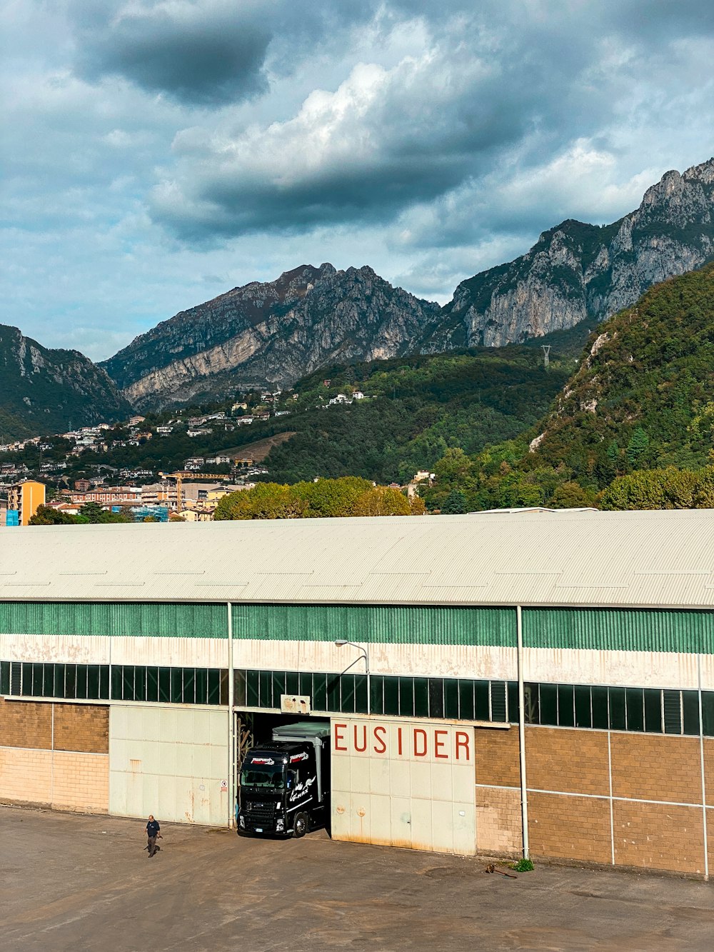 a truck parked in front of a building with mountains in the background