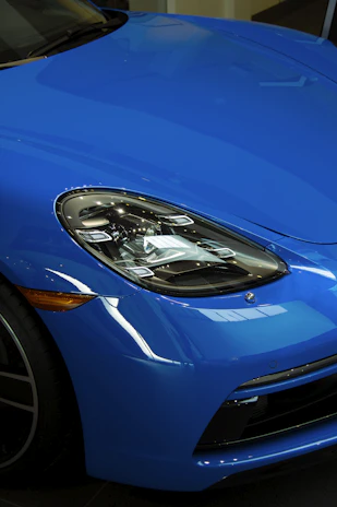 Close-up of a sleek blue sports car shining under showroom lights.