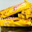 Three snack bars packaged in bright yellow wrappers are arranged, partially overlapping each other. The text on the wrappers indicates the brand and the word 'Original'. There are images of cereal pieces on the packaging. The bars seem to be crunchy cereal snacks likely from a known brand.