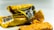 A close-up view of two crumpled, yellow snack wrappers with visible nutritional information in multiple languages. Pieces of a cereal bar are visible in the foreground.