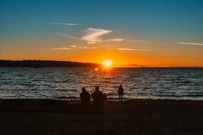 A beautiful sunset over the ocean with silhouettes of people.