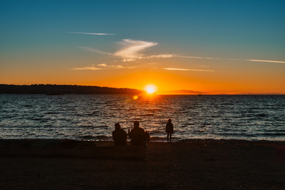 a couple of people sitting on top of a sandy beach