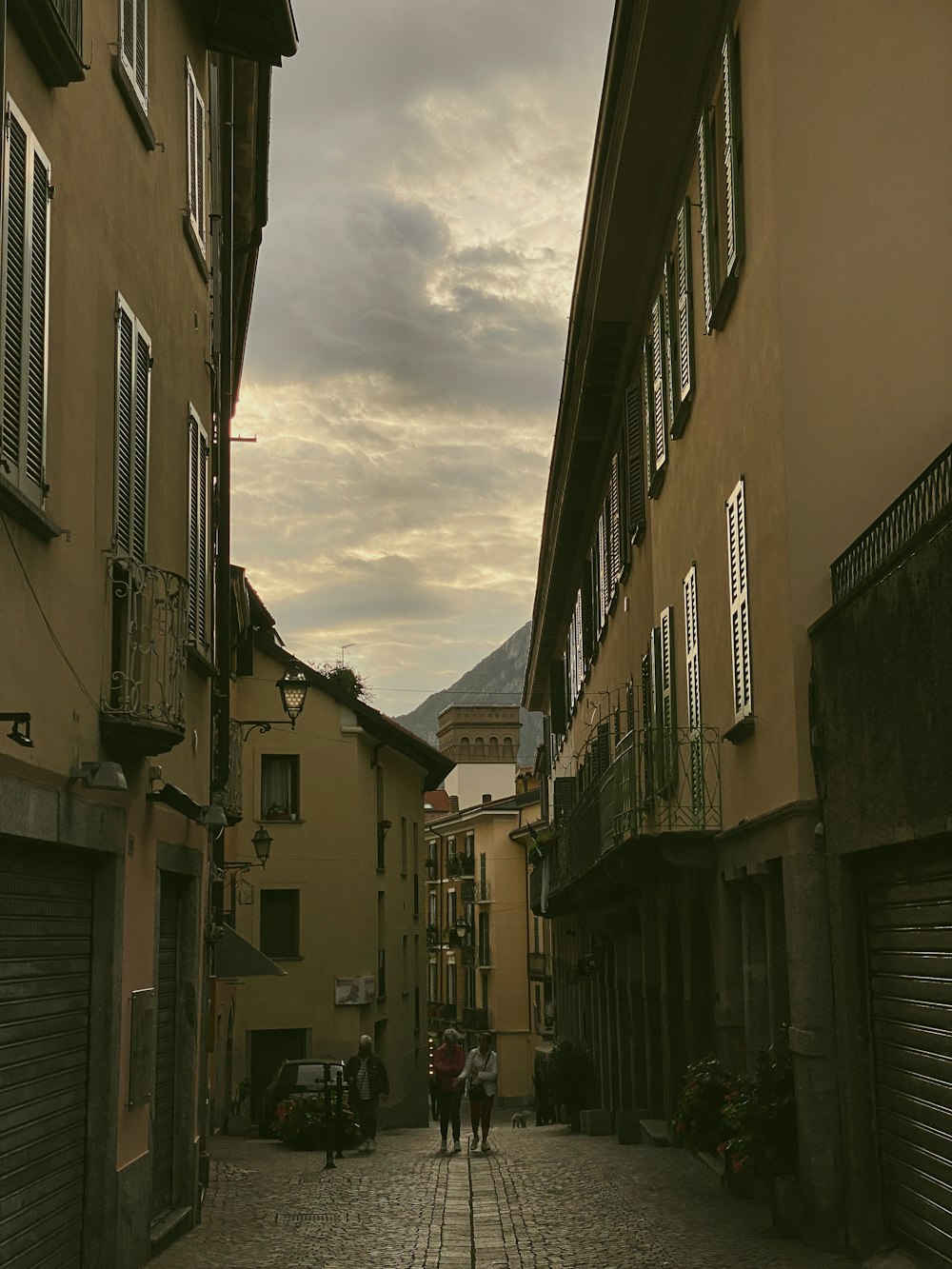 a couple of people walking down a street next to tall buildings