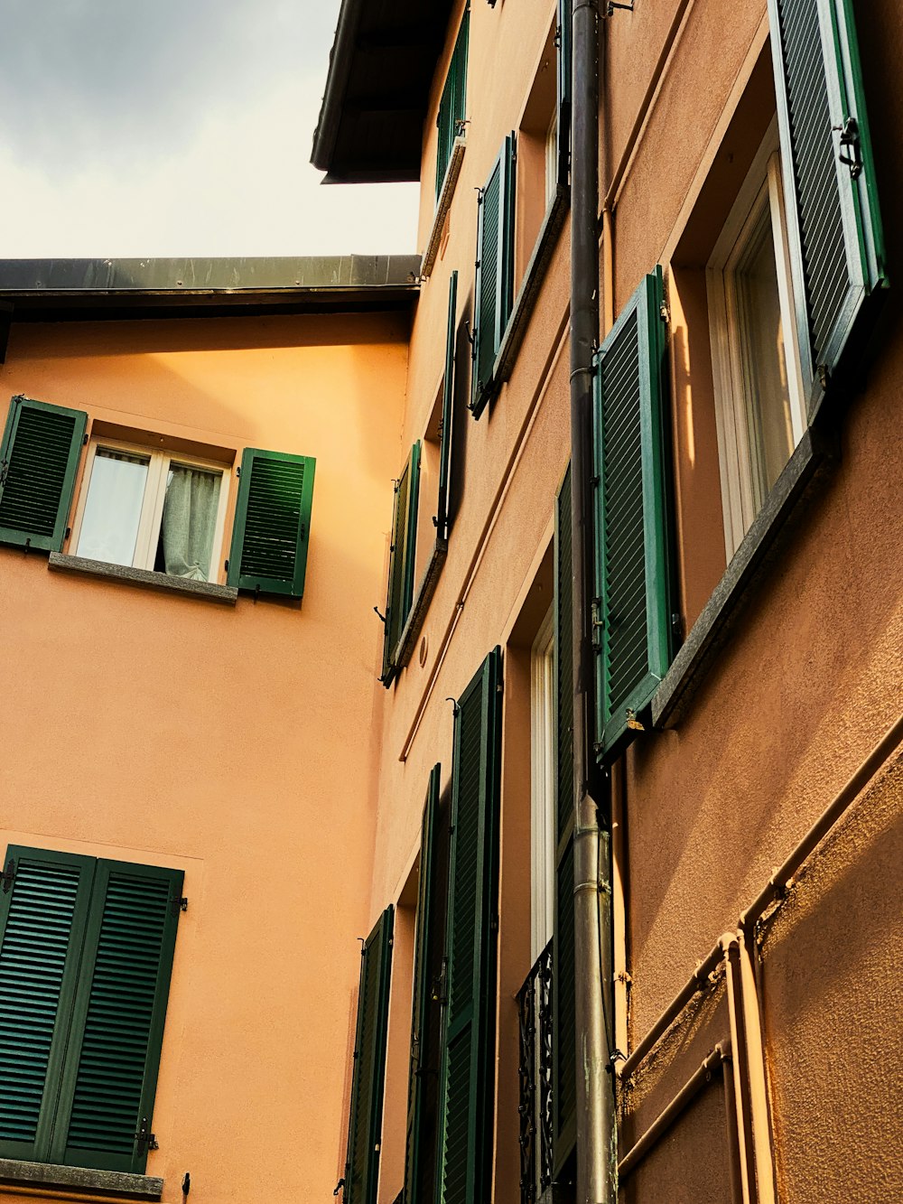 a tall building with green shutters next to a building