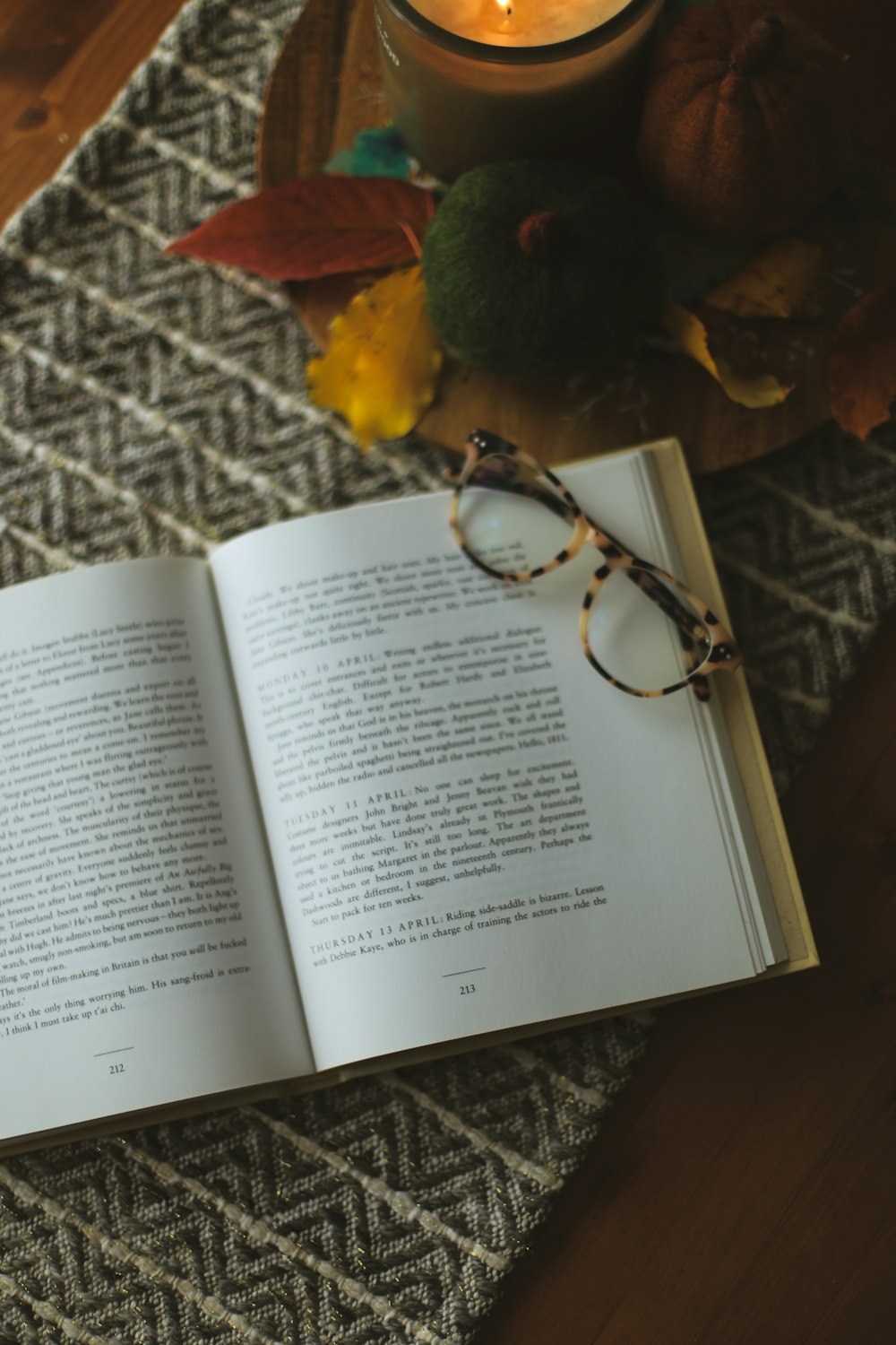 an open book sitting on top of a table next to a candle