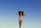 A person in a colorful, striped swimsuit poses confidently against a clear blue sky. The individual stands with arms raised, embracing their natural curly hair, conveying a sense of freedom and self-expression.