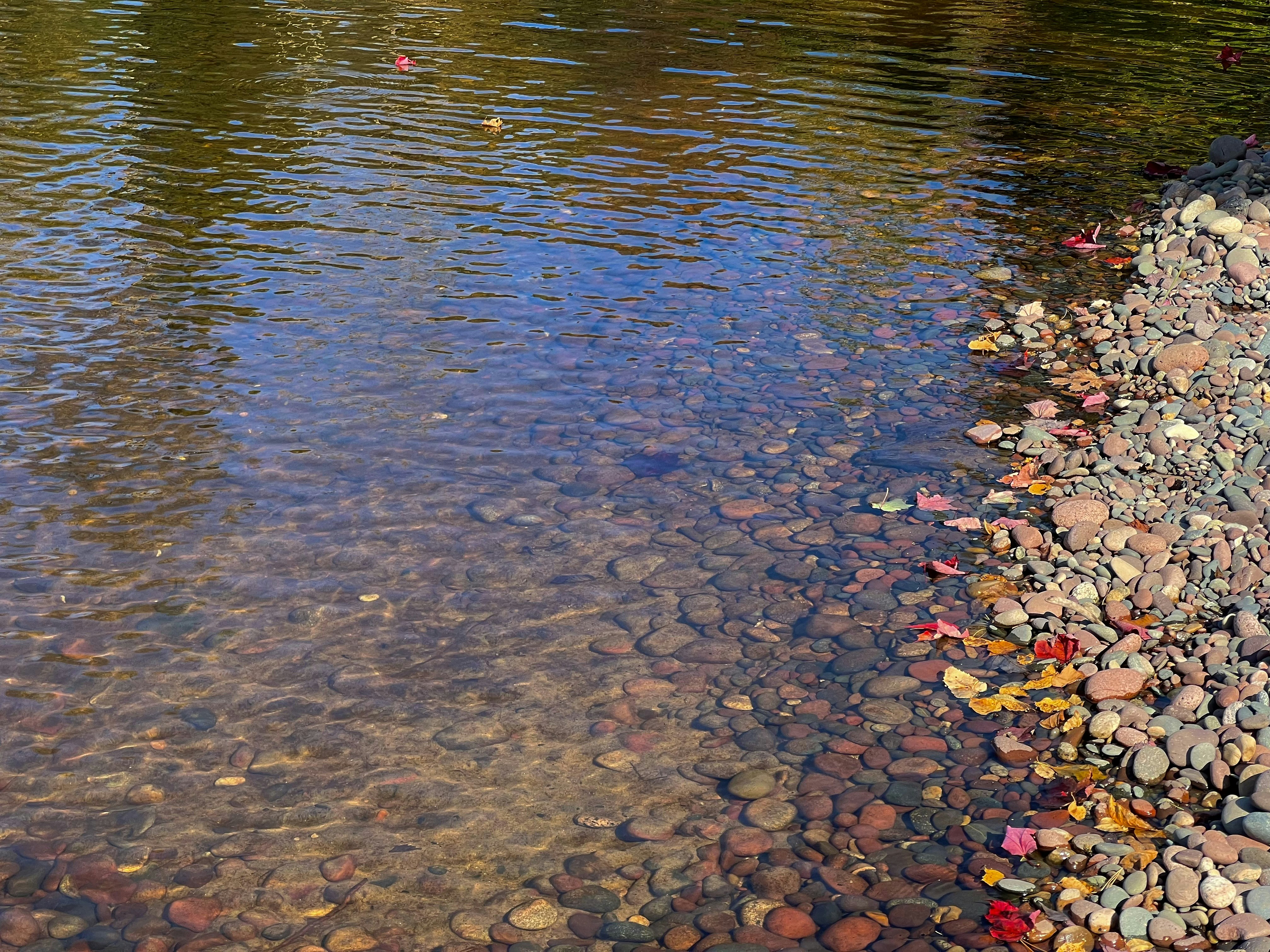 a body of water surrounded by rocks and pebbles, 
