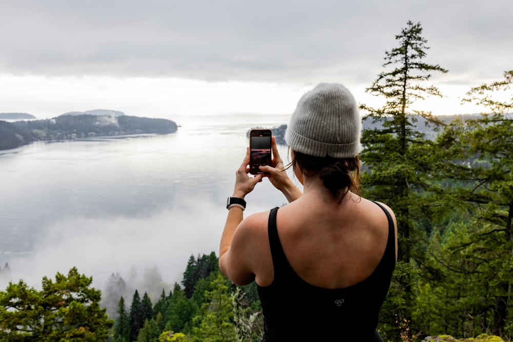 a woman taking a picture of a body of water