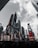 Skyscrapers rise against a cloudy sky, adorned with bright, large advertisements and digital billboards. The urban environment is dynamic, with various colorful ads promoting different brands and shows.