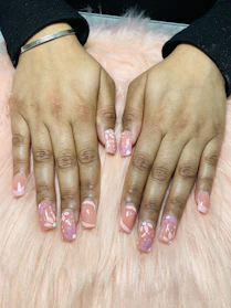 Elegant hands showcasing pastel nail designs with delicate floral patterns.