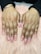Hands with freshly manicured nails featuring a glossy peach base color decorated with intricate floral patterns. The background consists of a soft pink, fluffy surface.
