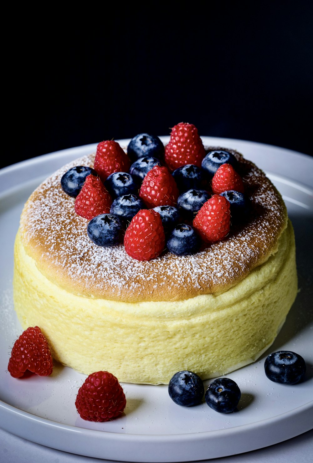 a cake with berries and powdered sugar on a plate