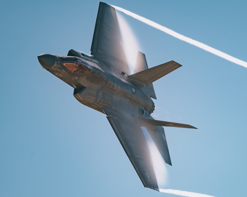 a fighter jet flying through a blue sky