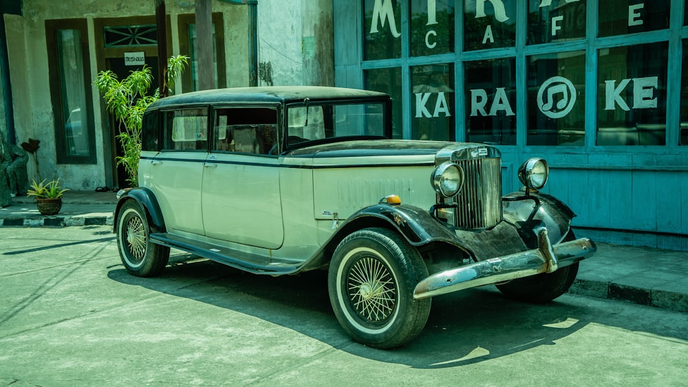 an old car is parked in front of a cafe
