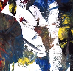 An abstract painting featuring bold, expressive brushstrokes in a mix of colors including blue, yellow, red, black, and white. The composition is dynamic and textured, creating a sense of movement and intensity.