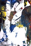 An abstract painting featuring bold brushstrokes and vibrant colors, including blue, yellow, red, and black, creating an intricate and textured composition on a white canvas.
