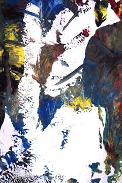 An abstract painting featuring bold brushstrokes and vibrant colors, including blue, yellow, red, and black, creating an intricate and textured composition on a white canvas.