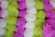 A collection of coiled translucent materials in vibrant colors including green, white, and pink. The texture appears soft and fibrous, resembling a kind of decorative or edible item.