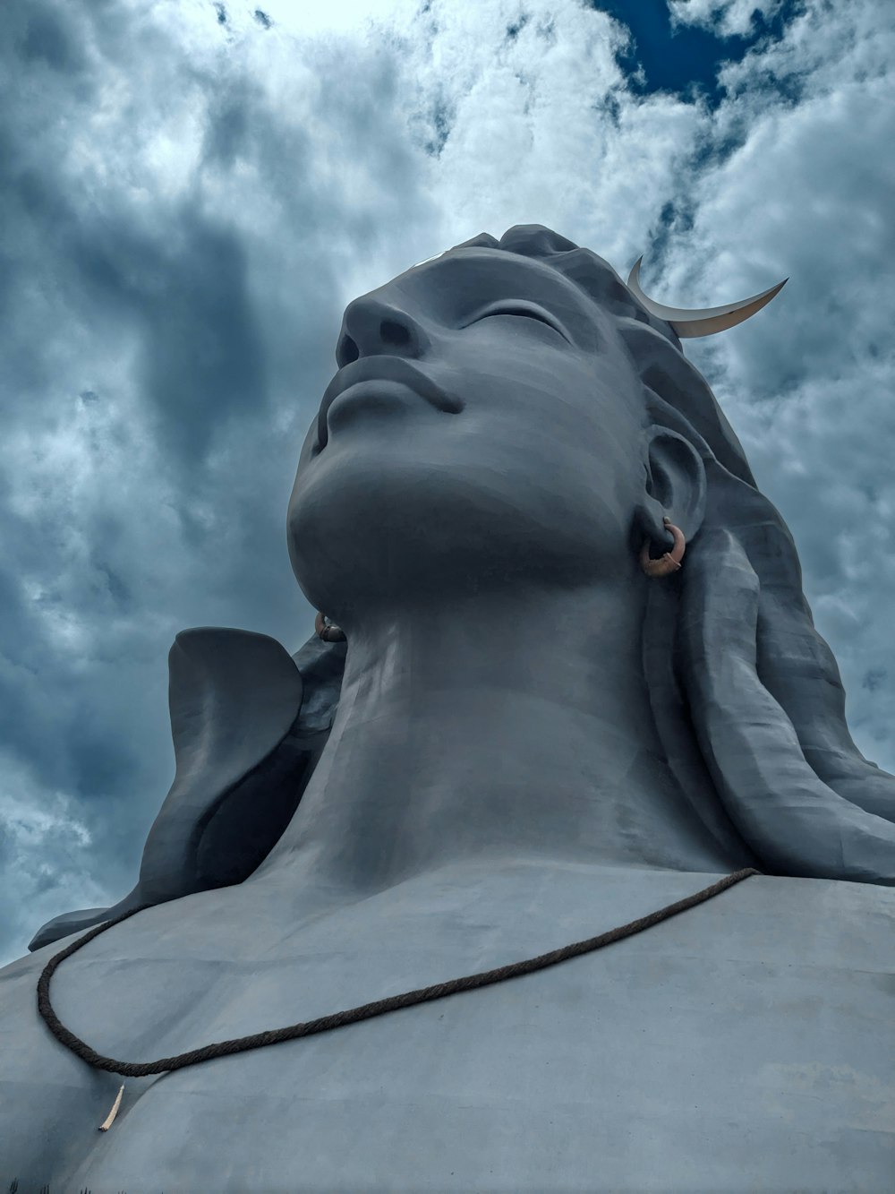 a close up of a statue with clouds in the background