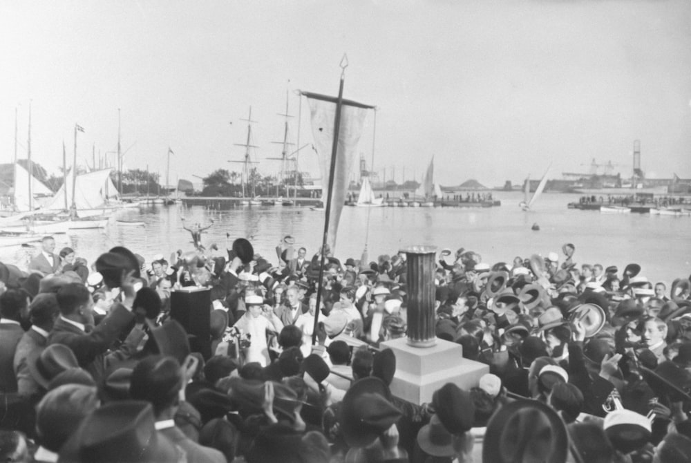 uma multidão de pessoas em pé ao redor de um barco na água