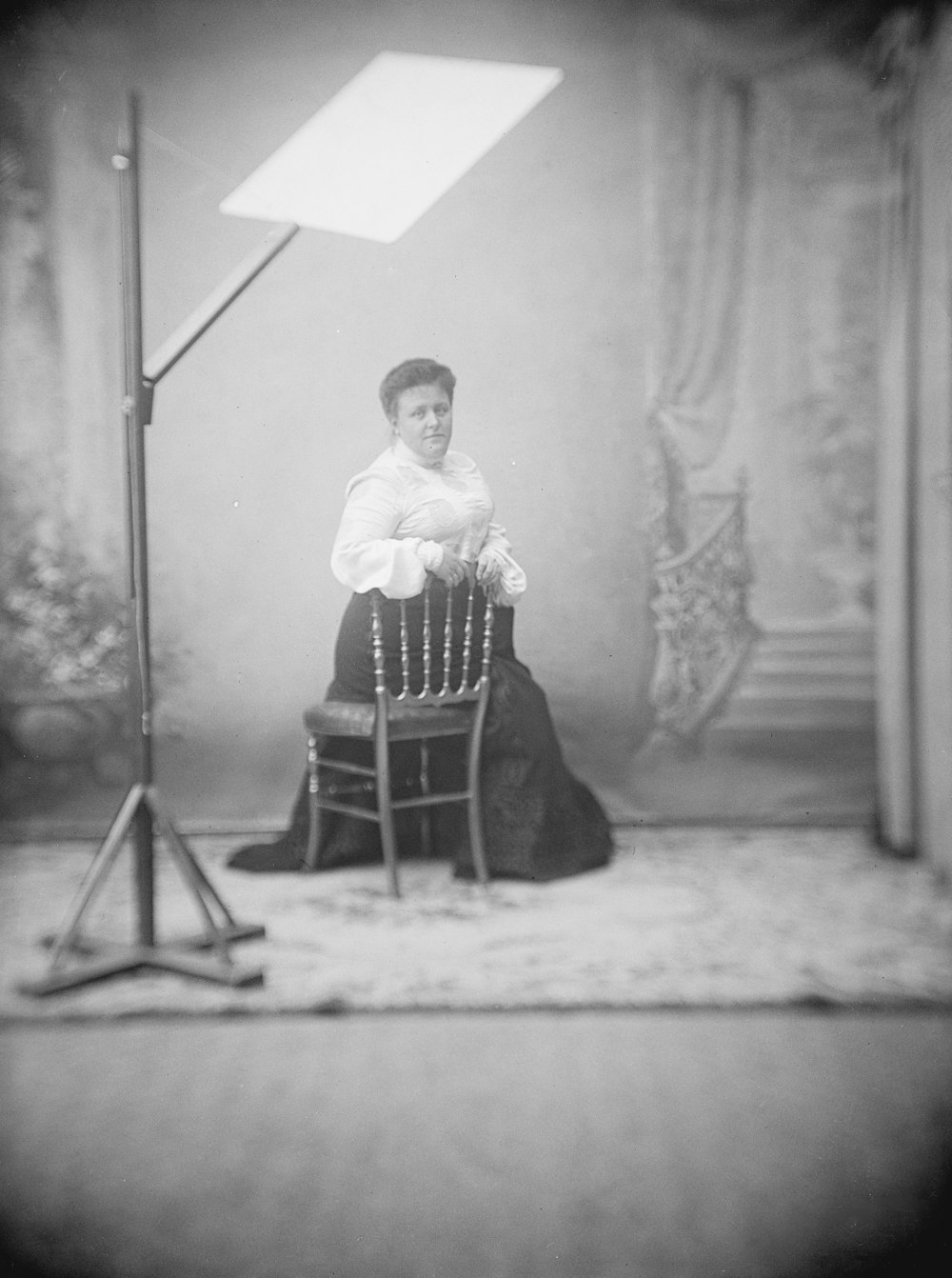 a woman sitting in a chair in front of a lamp