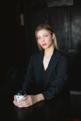 a woman sitting at a table with a drink in her hand