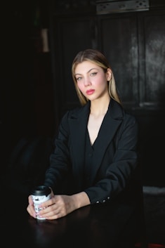 a woman sitting at a table with a drink in her hand